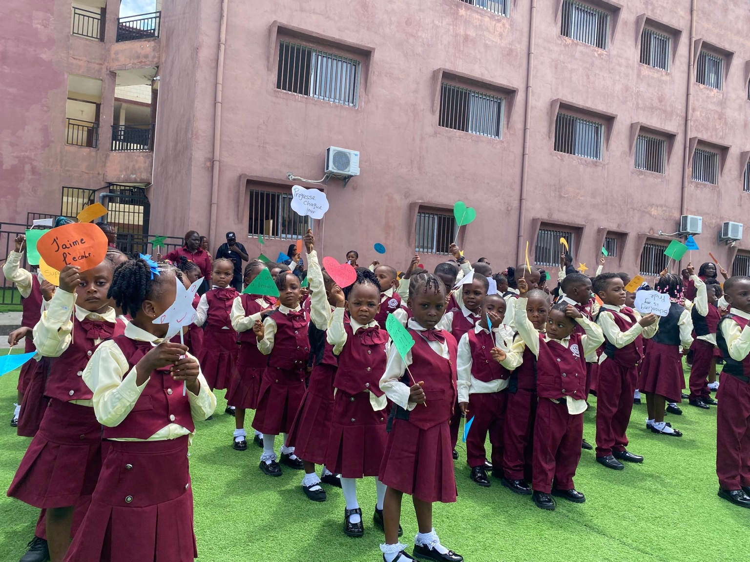 Pupils in official school uniforms holding colorful signs outside