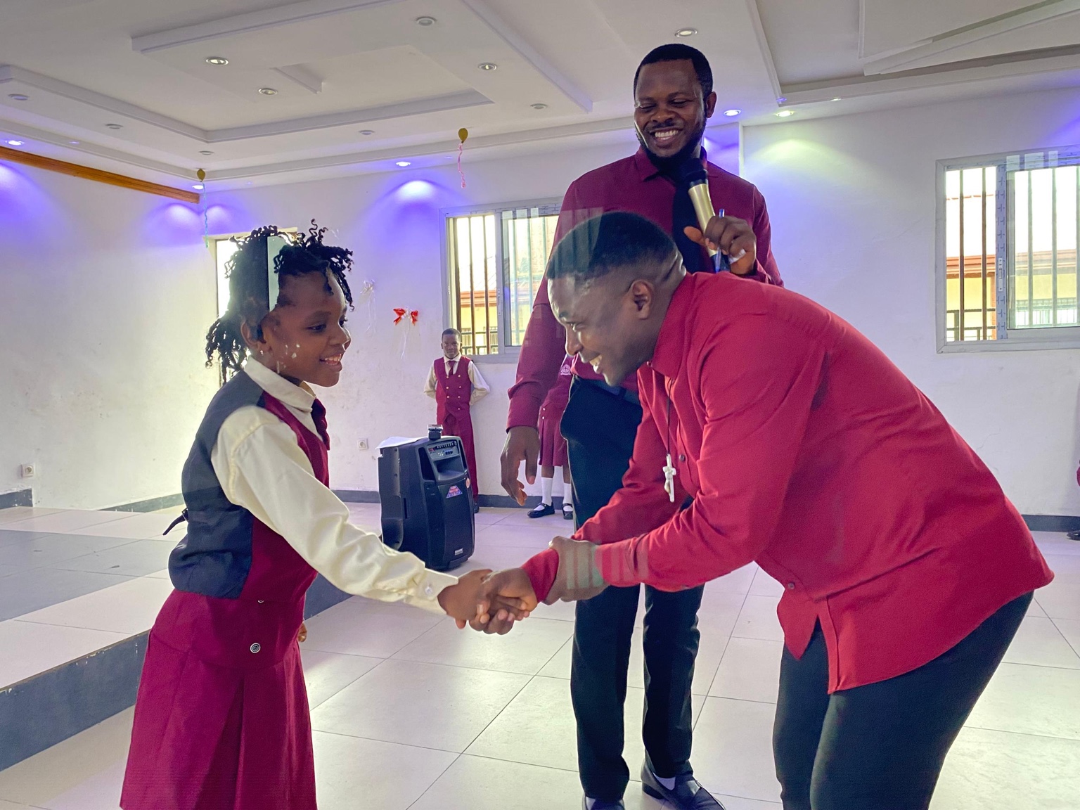 A pupil in school uniform greeting an adult at a school event