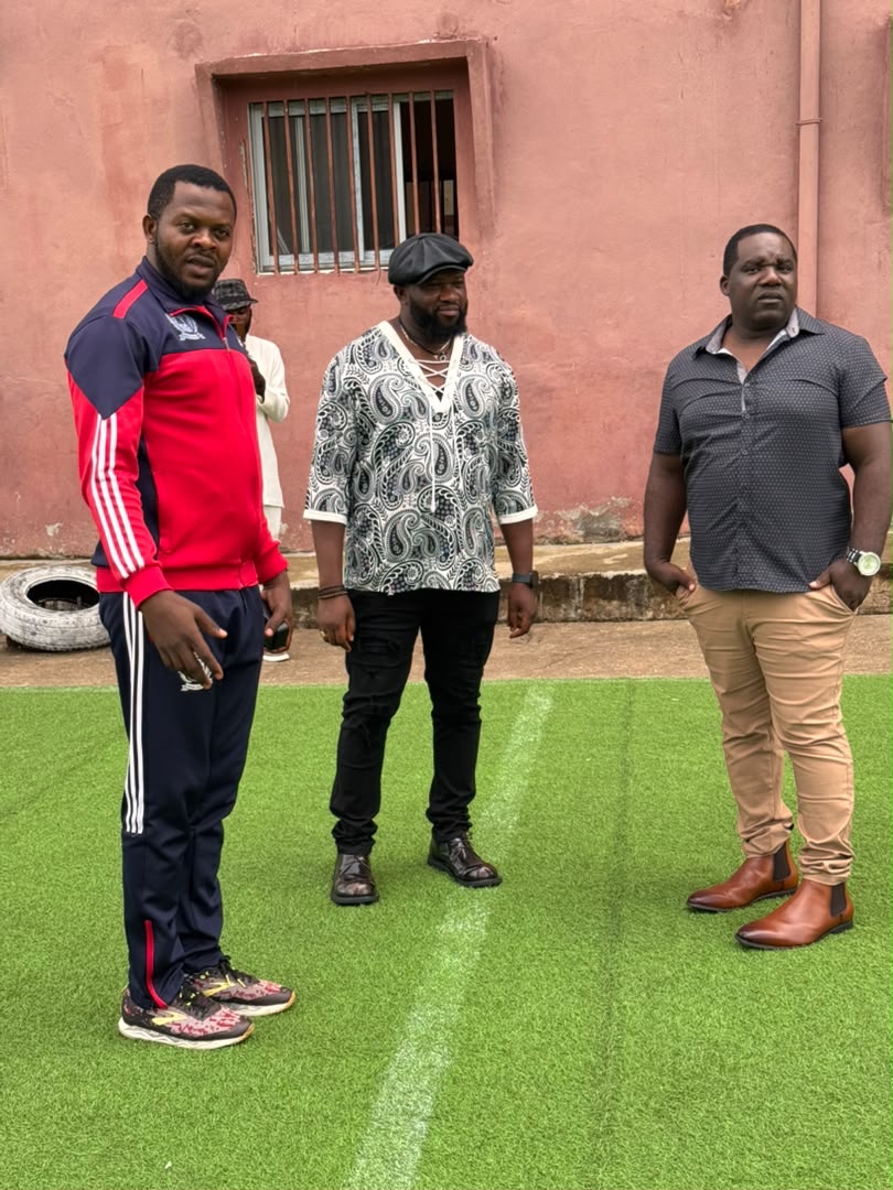 Three men standing on the school field during the visit